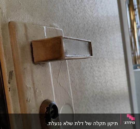 ידית דלת מתכתית על רקע דלת לבנה